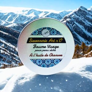 Baume visage nourrissant Savonnerie Art n’O, label rond sur neige avec montagnes en arrière-plan.