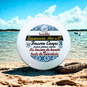 Baume corps Vanille 150 ml en boîtier blanc posé sur le sable au bord de l’eau, label Savonnerie Art n’O, détails: vanille, karité, calendula.