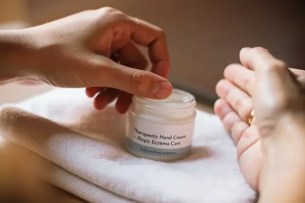Pot de crème thérapeutique pour les mains sur un comptoir de salle de bain pour le traitement quotidien de l'eczéma atopique.