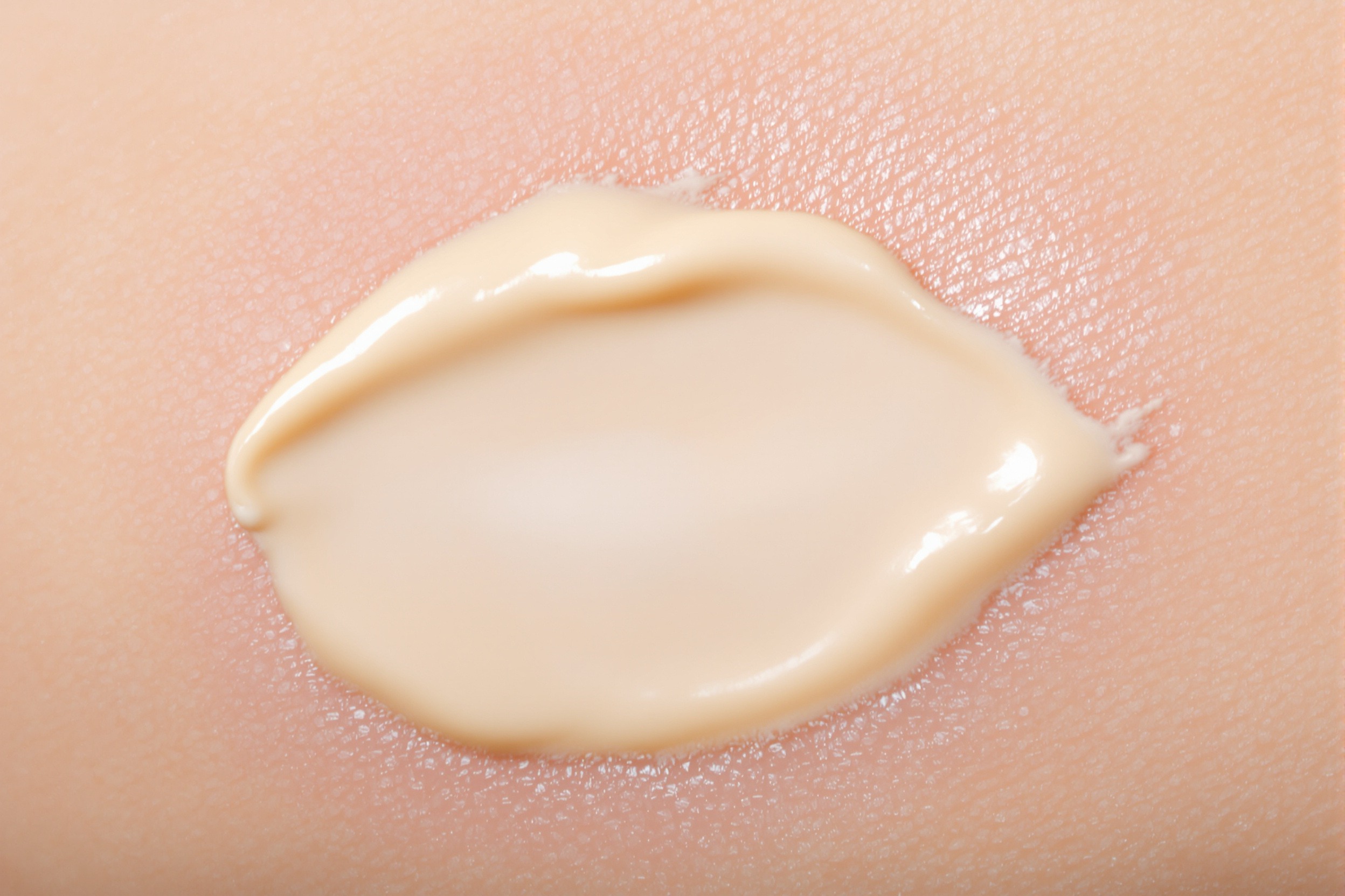 Goutte crémeuse de baume apaisant beige sur peau peau saine, texture lisse et hydratante.