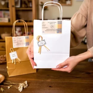 Sac cadeau blanc élégant avec ruban doré et étiquette “Savonnerie Art n'O” – presenté en boutique.