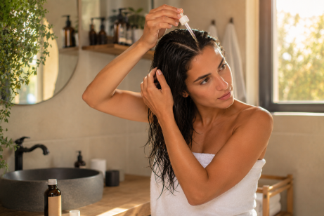 Une femme dans une salle de bain va entretenir ses cheveux abimés