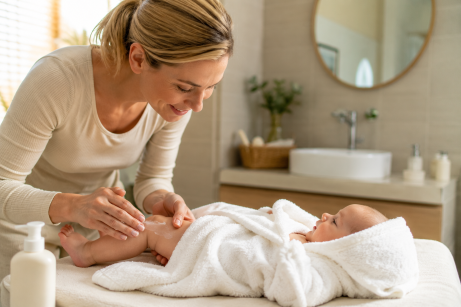 massage de la peau des bébés. Une maman applique un baume sur les jambes de son enfants.